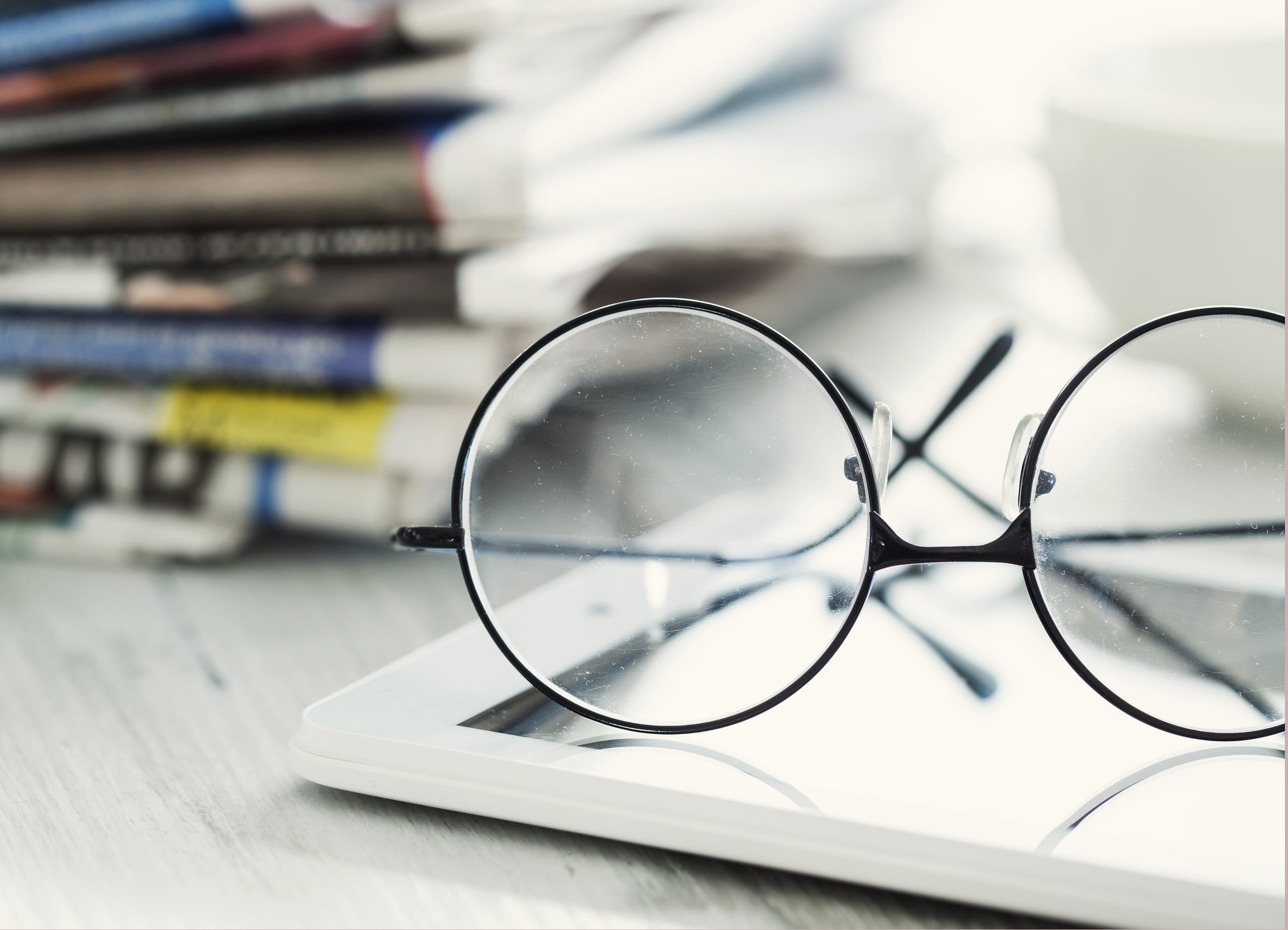 Stack of newspapers, eyeglasses and digital tablet