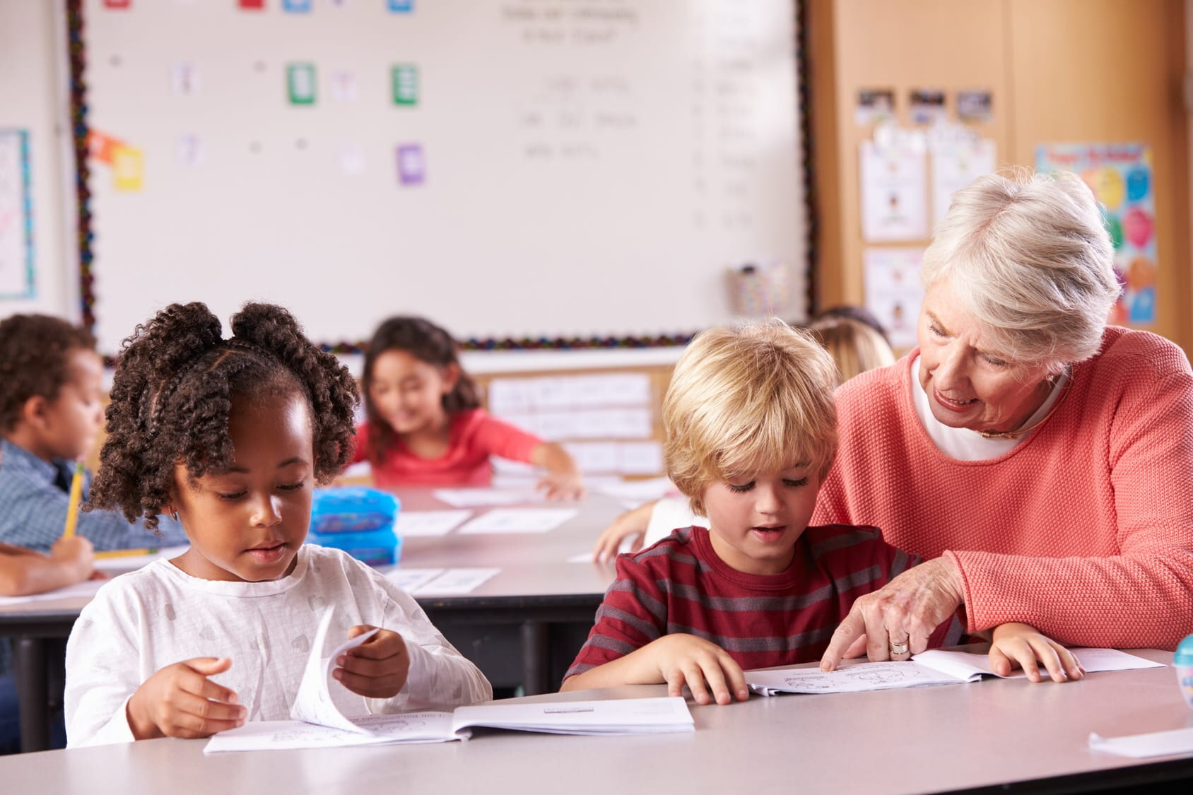 Senior teacher helping elementary school pupil in class