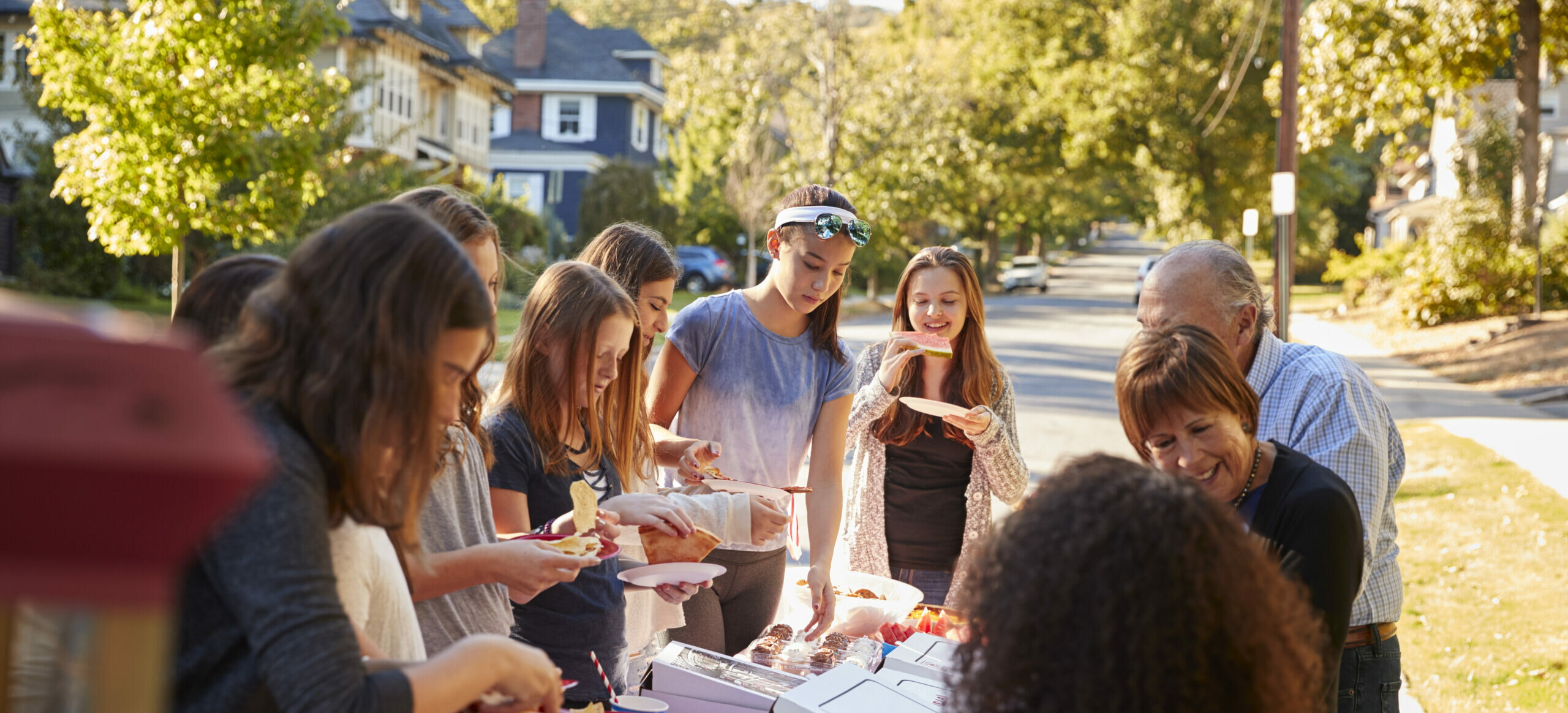 Neighbours Standing Around A Table At A Block Party